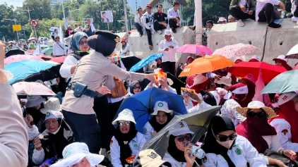 Polisi Bagikan Air Mineral dan Roti kepada Massa Aksi Damai Guru di Silang Selatan Monas